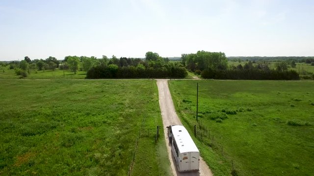 Aerial horse trailer starts its ride up a rural dirt road, Kansas, Missouri. Concept: ranch life, rural, midwest