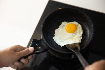 Close up of hands holding spatula to stir fry scrambled eggs carefully on hot pan