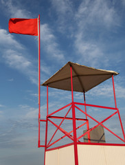 waving big red flag on the turret of lifeguard the in summer