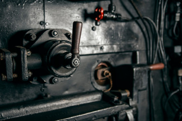 Metal lever mechanism with a wooden handle in the cabin of the locomotive, industrial background.