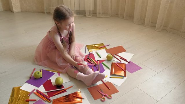 little girl draws on her feet with felt-tip pens, children's creativity, development