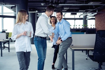 Taking their business on the move. Full length of young modern people in smart casual wear having a discussion while walking through the large modern office.