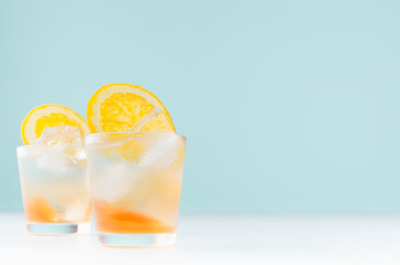 Summer fresh alcoholic drinks with oranges liquor, ice cubes in shot glass on blue wall, copy space.