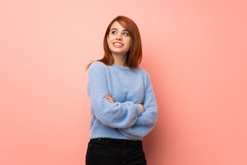 Obraz premium Young redhead woman over pink background looking up while smiling