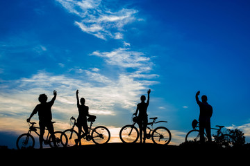 Cyclists waving with hands on evening sunset sky. Tourists enjoying beauty of evening nature. Life energy and freedom.