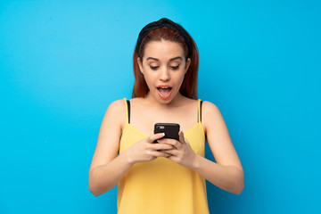 Young redhead woman over blue background surprised and sending a message