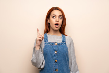 Young redhead woman over isolated background thinking an idea pointing the finger up