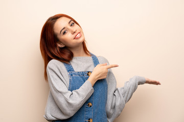 Young redhead woman over isolated background holding copyspace imaginary on the palm to insert an ad