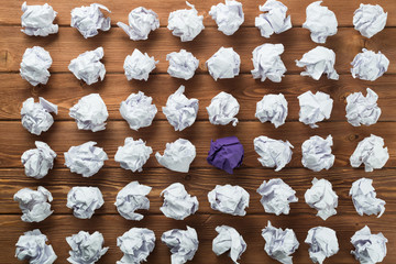 Concept of creativity and inspiration presented by many white paperballs and one color