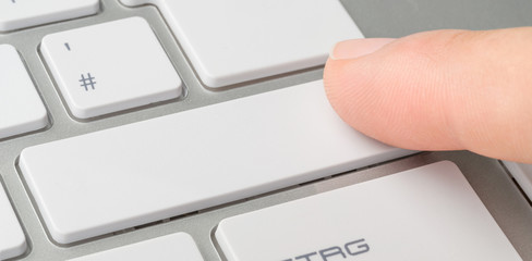 A finger clicking an unlabeled button on a keyboard