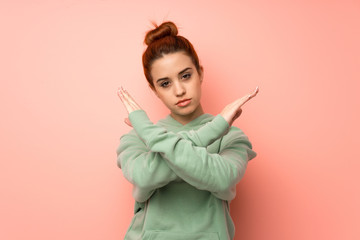 Young redhead woman with sweatshirt making NO gesture