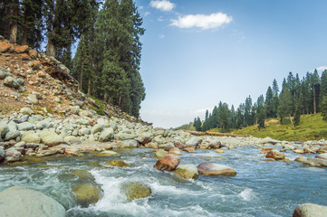 A crystal clear stream with blue waters flowing through a wide mountain valley in Doodhpathri, Kashmir
