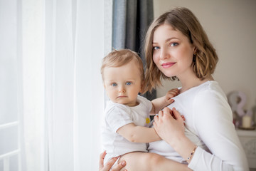 Beautiful mother and little son 9 months in the home interior. Cozy. Baby. Motherhood.