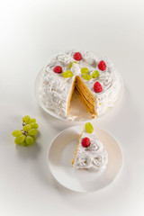 Creamy homemade cake made from natural ingredients with raspberries and grapes on a white background.