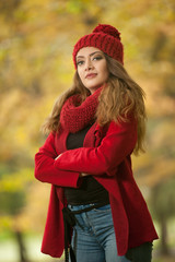 Happy Portrait fashion of a beautiful young Caucasian woman with a red cap and scarf and red jacket in autumn park, red green yellow threes. Autumn, season and people concept.Autumn lifestyle