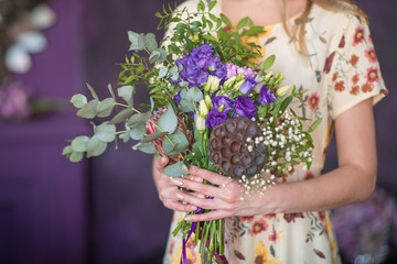 Adorable bouquet of flowers in the tender hands of a girl on a dark background. general view.