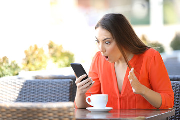 Amazed woman checking phone finding good news