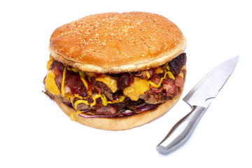 Huge delicious juicy burger with bacon, beef cutlets, fresh lettuce, tomatoes, sauce, onion, cheese and white fresh bun with sesame