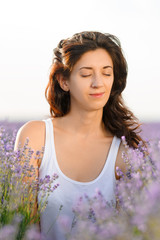 Portrait of a beautiful brunette in a lavender field. She closed her eyes in pleasure.