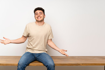 Young man sitting on table smiling
