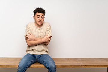 Young man sitting on table freezing