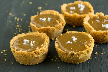 Salted caramel tartlets on rustic black background