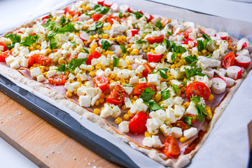 Homemade raw pizza with colorful vegetables and white mozzarella cheese just ready for the oven to bake