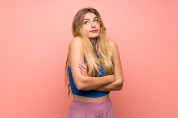 Young blonde woman over isolated pink background making doubts gesture while lifting the shoulders