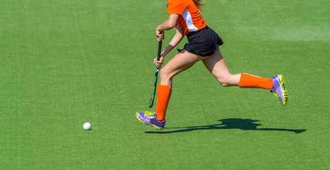 Obraz premium Young hockey player woman with ball in attack playing field hockey game