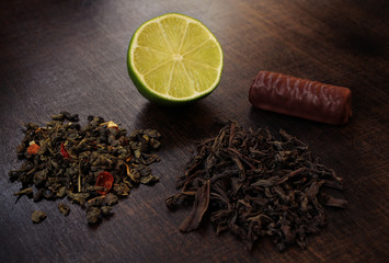 Black and green tea with lime, lemon and chocolate on a wooden table