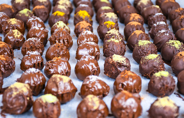 Group of sweet and tasty homemade chocolate balls on a backing paper sprinkled with different spice flavors close up