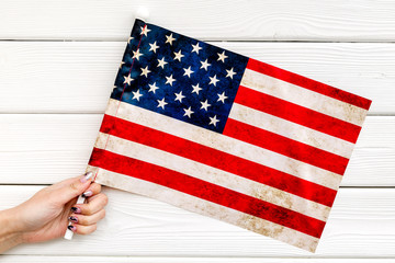 Memoral day of United States of America with flag in hand on white wooden background top view
