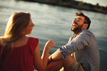 Young couple in love flirting by the river at sunset