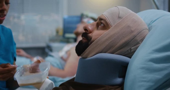 Nurse feeding injured soldiers in hospital bed