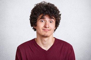 Close up portrait of handsome male model with crisp hair, posing with misunderstanding facial...