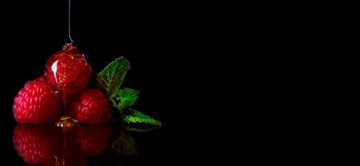 Raspberries on dark background with reflections on the table