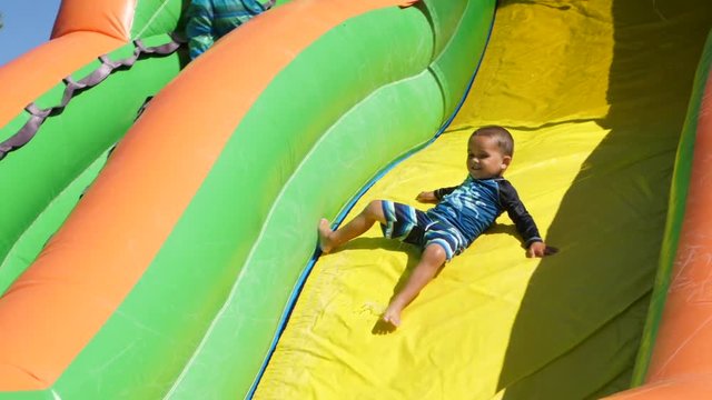 Slow motion shot of boy sliding down an inflatable water slide