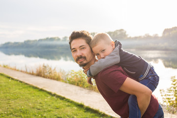 Family, childhood, fatherhood concept - Father piggyback his little son outside