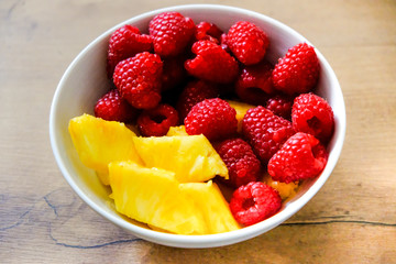 Ananasstücke und Himbeeren in einer Schale