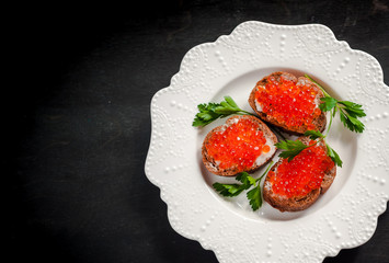 red caviar on black bread with butter. Healthy food. Fish appetizer. dark background
