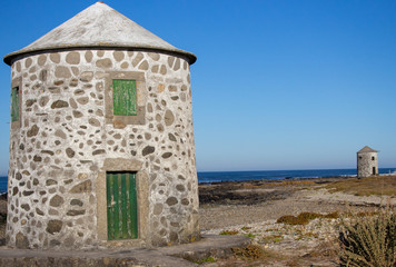Fototapeta na wymiar Abandoned old lighthouse with closed green door and windows on Atlantic ocean coast, Portugal. Lighthouse behind wooden fence. Medieval architecture. Landscape on Camino de Santiago. 