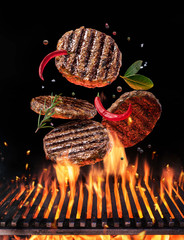 Beef milled meat on hamburger with spices fly over the flaming grill barbecue fire. - obrazy, fototapety, plakaty