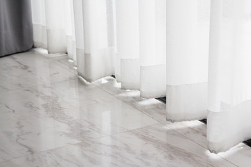 white transparent curtain over marble floor. lace curtain of house window.