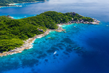 Aerial drone view of boats around the shallow coral reef surrounding beautiful tropical islands (Similan Islands)