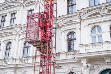 Fototapeta na wymiar Facade restoration concept. Beautiful historic Prague house and scaffold elevator