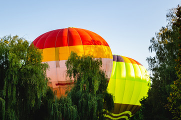Colorful hot air balloon is flying in the blue sky above the trees
