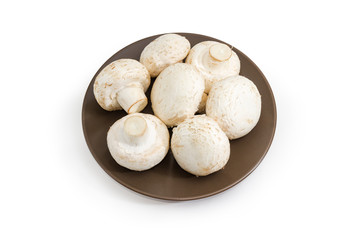 Uncooked cultivated button mushrooms on a brown dish