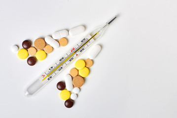 thermometer with pills on a white background with copyspace