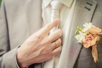 At the wedding, the bride and groom straighten the tie on the suit of the groom. Close-up.