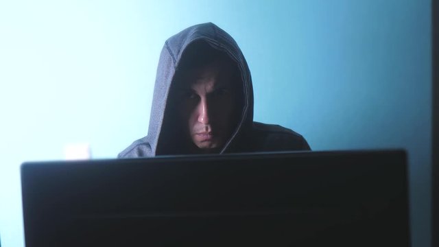 man hacker in the hood concept. unknown hacker criminal breaks into computer protection on the Internet passwords. male hacker lifestyle penetrates into hack network protection web phishing technology